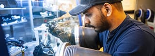 A man with a ball cap conducts research through a fume hood
