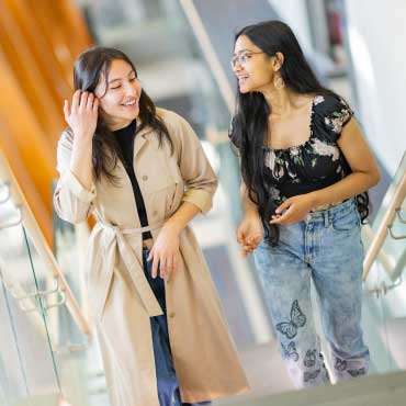 Two students walking up the stairs at the AMS Nest.