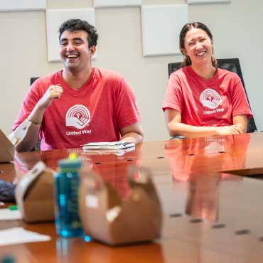UBC United Way Campaign volunteers smiling while sitting at a table.