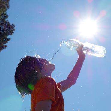 Child drinking water under the sun.