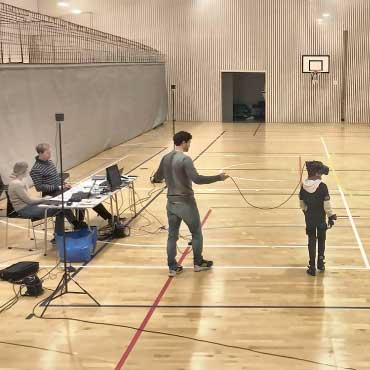 A child prepares to undertake a task in a gymnasium while wearing a virtual-reality headset.