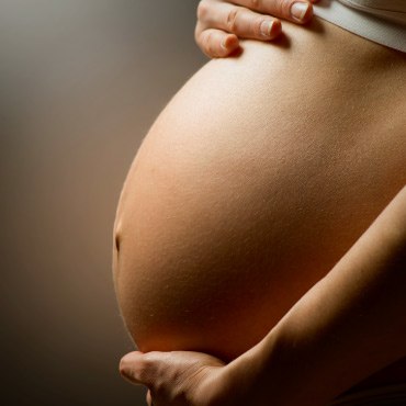 Close-up of a pregnant person&rsquo;s abdomen.