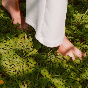 Person walking on grass with bare feet.